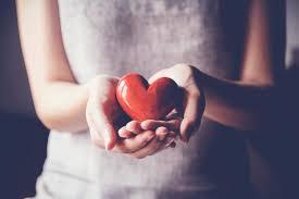 woman holding wooden red heart in her hands